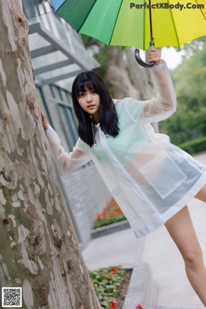 A woman in a white shirt and blue shorts holding an umbrella.