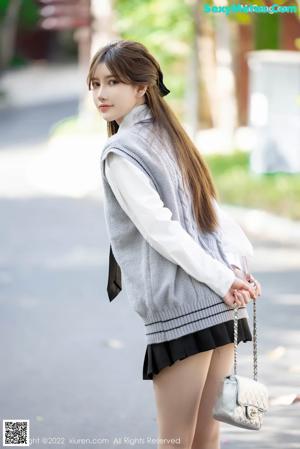 A young woman wearing a gray vest and a black tie.