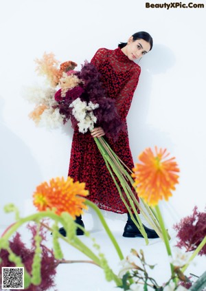 A woman in a black dress laying on a bed of flowers.