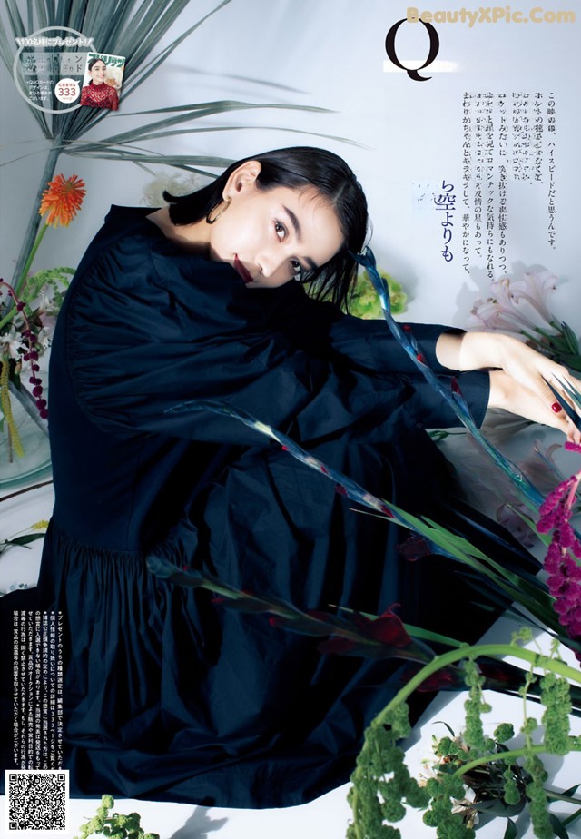 A woman in a black dress laying on a bed of flowers.
