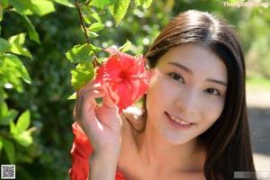 A woman in a red top and denim shorts posing for a picture.