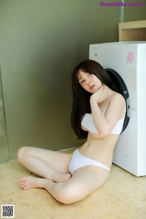 A woman sitting on top of a washing machine.