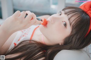 A woman in a red and white bikini sitting on a white couch.