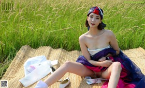 A naked woman standing in a field of tall grass.