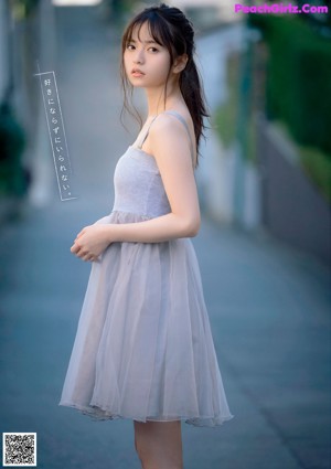 A woman in a white shirt and blue skirt holding a glass of water.