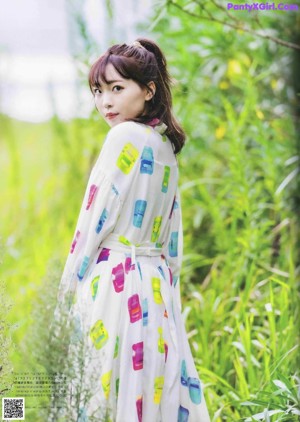 A woman in a white dress sitting on a grassy field.
