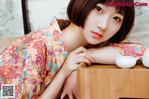 A woman laying on the floor in a kimono.