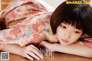 A woman laying on the floor in a kimono.