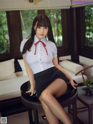 A woman in a short skirt and high heels posing on a table.