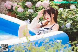 A woman in a bikini standing next to a pool.