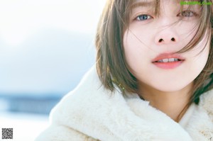 A close up of a woman's face with a white fur coat.