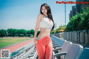 A woman in a white top and red leggings posing for a picture.