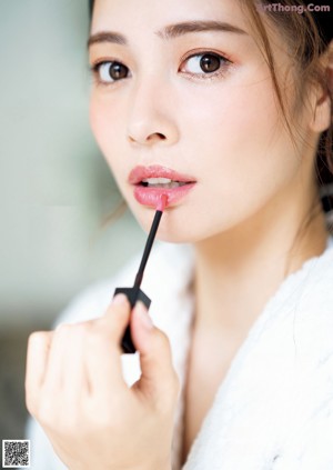 A woman applying lipstick on her lips. 