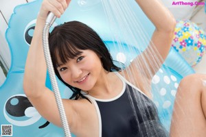A woman in a bathing suit standing in the shower.