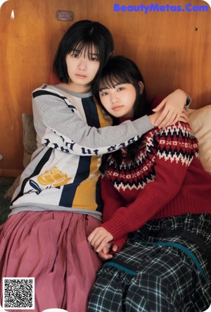 A couple of young people laying on top of a bed.