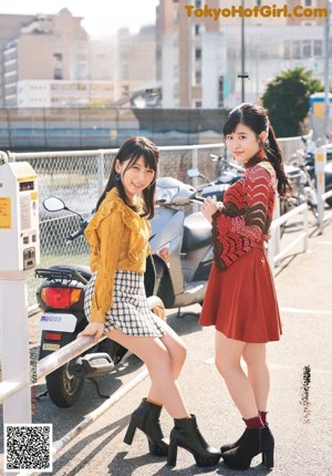 Two young women standing next to each other near a window.