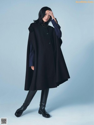 A woman in a black coat holding a red bag.