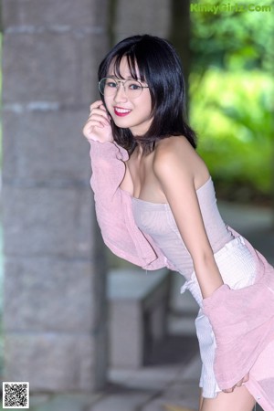 A woman wearing glasses and a pink cardigan posing for a picture.