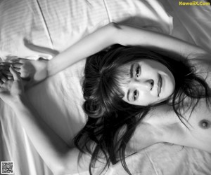 A naked woman sitting on a tatami mat in a room.