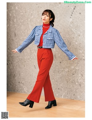 A woman in a blue sweater leaning against a wall.