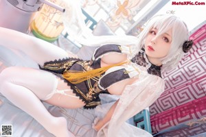 A woman in a maid outfit sitting on a chair.