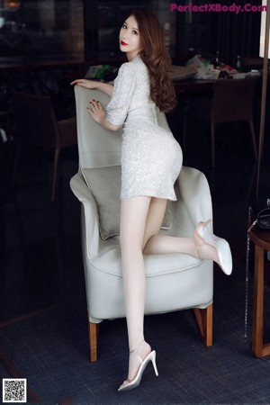 A woman in a silver dress sitting on a couch.
