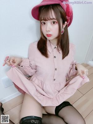 A woman in a pink hat and black stockings is sitting on the floor.