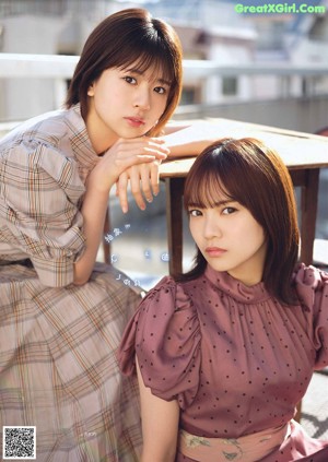 A couple of young women laying on top of a bed.