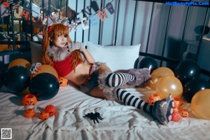 A woman in a cat costume sitting on a bed.
