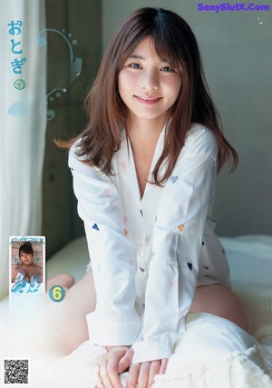 A woman in a white lingerie sitting on a blanket.