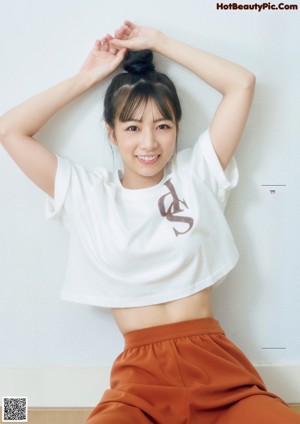 A woman in a white shirt and orange skirt smiles at the camera.