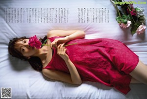 A woman in a red dress laying on a bed.