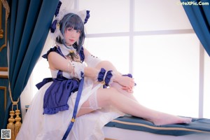 A woman in a blue and white dress sitting on a chair.