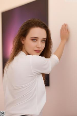 A woman in a white shirt is posing for the camera.