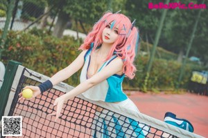 A woman with pink hair sitting on a tennis court.