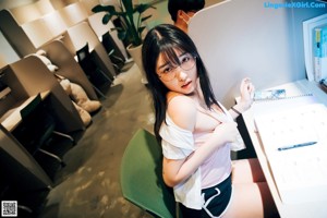 A woman sitting on a green chair in an office.